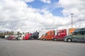 Colorful big rigs semi trucks with different semi trailers standing in row on truck stop parking lot taking break for truck Royalty Free Stock Photo