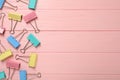 Colorful binder clips on pink wooden background, flat lay. Space for text Royalty Free Stock Photo