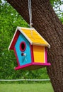 A colorful birdhouse hanging from a tree