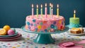 Colorful birthday cake with festive candles stand on a table with a subtly patterned tablecloth Royalty Free Stock Photo