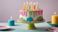 Colorful birthday cake with festive candles stand on a table with a subtly patterned tablecloth Royalty Free Stock Photo