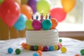 A colorful birthday cake with lit candles is placed on a table adorned with festive balloons, Balloons in the shape of a birthday Royalty Free Stock Photo