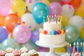 Colorful birthday cake with lit candles surrounded by balloons and confetti Royalty Free Stock Photo