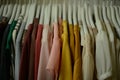 colorful blouses hanging on white hangers, arranged by color