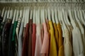 colorful blouses hanging on white hangers, arranged by color