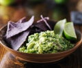 Colorful blue corn tortilla chips with fresh mexican guacamole and lime wedges