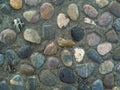 Colorful blue gray pink orange round and smooth stones of the same size in a cement path in a city park. Design