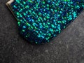 Colorful blue and green mixed round iridescent sequins, beads on knitting fabric for holiday, festive beautiful colorful