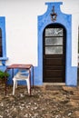 Colorful blue wall facade, door, and table and chairs in the small village of Alte, Portugal