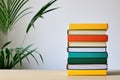 Colorful Books Stacked on Wooden Surface with Plant Background Royalty Free Stock Photo