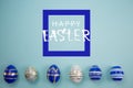 Colorful border of blue and white Easter eggs on the blue background. Flat lay, Top view. Lettering Happy Easter.
