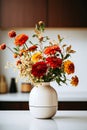 Colourful bouquet of autumn flowers in white vase stands on white table in the kitchen. Concept of style and minimalism in