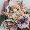 Colorful bouquet of different fresh flowers in the hands of florist woman. Rustic flower background. Craft bouquet of