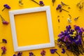 Colorful bouquet of dried autumn flowers lying on a white frame on yellow paper background. Copy space. Flat lay. Top view. Royalty Free Stock Photo