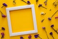 Colorful bouquet of dried autumn flowers and white wooden frame lying on yellow paper background. Copy space. Flat lay. Royalty Free Stock Photo