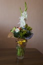 Colorful bouquet with such flowers as gladiolus, orchid, roses, callas, mimosa are standing in the big glasses vase. Tints of whit Royalty Free Stock Photo