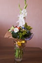 Colorful bouquet with such flowers as gladiolus, orchid, roses, callas, mimosa are standing in the big glasses vase. Tints of whit Royalty Free Stock Photo