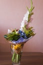 Colorful bouquet with such flowers as gladiolus, orchid, roses, callas, mimosa are standing in the big glasses vase. Tints of whit Royalty Free Stock Photo