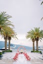 Colorful bouquets of flowers stand along the path to a round wedding arch with white rows of chairs