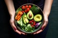 Colorful bowl with avocado and vegetables in a woman& x27;s hands