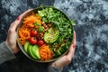 Colorful bowl with avocado and vegetables in a woman& x27;s hands