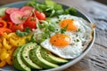 A colorful breakfast platter with fried eggs, fresh vegetables, and avocado slices