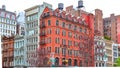 Colorful brick buildings, with windows and fire stairs. Water deposits on rooftops. NYC.