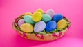 Colorful bright Easter eggs inside basket on pink background Royalty Free Stock Photo