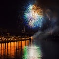 Colorful bright fireworks, salute of various colors in night sky with reflection in the lake. Abstract square holiday Royalty Free Stock Photo