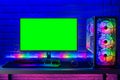 Colorful bright illuminated rgb gaming pc with keyboard mouse monitor with green screen copy space front of LED light brick stone Royalty Free Stock Photo