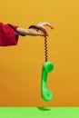 Colorful bright image of female hand holding old-fashioned green colored phone, handset isolated over yellow background Royalty Free Stock Photo