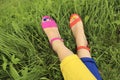 Colorful bright pedicure in different pink and orange sandals and different blue and yellow pants Royalty Free Stock Photo