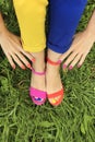 Colorful bright pedicure in different pink and orange sandals and different blue and yellow pants Royalty Free Stock Photo