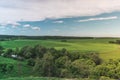 Colorful Bright Sunny Green Field Landscape With Blue Cloudy Sky, Trees And Hills