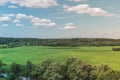 Colorful Bright Sunny Green Field Landscape With Blue Cloudy Sky, Trees And Hills