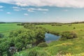 Colorful Bright Sunny Summer Green Field Landscape With Blue Cloudy Sky, River Trees And Hills