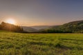 Bright sunrise rural panoramic landscape with a wide view over fields, forest, hills and misty valleys towards the Royalty Free Stock Photo