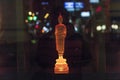 colorful buddha statue in a shop with reflection of street light in glass window by night