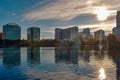 Colorful buildings and beautiful sunset with sun reflected in lake in Orlando Downtown area.