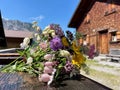 Colorful bunch of alpine flowers in fountain, traditional wooden huts in the background. Royalty Free Stock Photo
