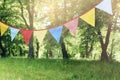 Colorful bunting flags hanging in park. Summer garden party. Outdoor birthday, wedding decoration. Midsummer, festa Royalty Free Stock Photo