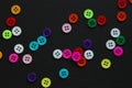 Colorful buttons sprinkled across black paper, forming a pattern with negative space Royalty Free Stock Photo