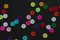 Colorful buttons sprinkled across black paper, forming a pattern with negative space Royalty Free Stock Photo