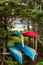 Colorful Canadian canoes stacked in rows in the forest near the lake. Royalty Free Stock Photo