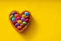 Colorful Candy Buttons on Heart shaped cake on yellow Background - Birthday concept Background