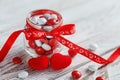 Colorful candy jar decorated with a red bow with hearts on white wooden background. Valentines day concept Royalty Free Stock Photo