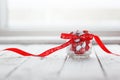 Colorful candy jar decorated with a red bow with hearts on white wooden background. Valentines day concept Royalty Free Stock Photo