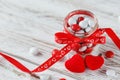 Colorful candy jar decorated with a red bow with hearts on white wooden background. Valentines day concept Royalty Free Stock Photo