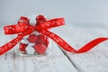 Colorful candy jar decorated with a red bow with hearts on white wooden background. Royalty Free Stock Photo