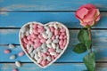 Colorful candy in white heart shaped bowl and white roses on w Royalty Free Stock Photo